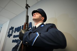 Zdjęcie. Widoczny umundurowany policjant stojący w korytarzu