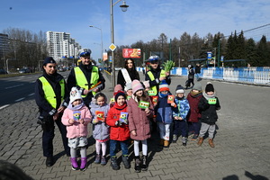 zdjęcie kolorowe przedstawiające dzieci z przedszkola, policjantów i Miss Polski stojących na chodniku