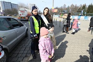 zdjęcie kolorowe przedstawiające policjantkę, Miss Polski i dwie dziewczynki stojące na chodniku,  w tle samochody