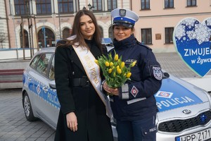 zdjęcie miss polski oraz policjantki która trzyma kwiaty w tle radiowóz