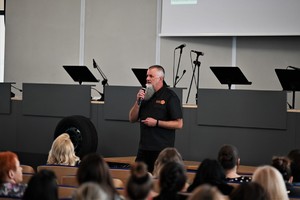 zdjęcie kolorowe w auli komendy, mężczyzna stojący na środku sali prowadzący wykład