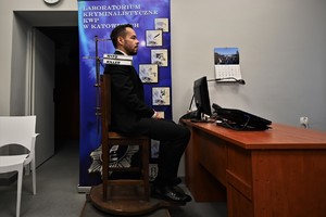 zdjęcie przedstawia mężczyznę siedzącego na zabytkowym drewnianym fotelu do robienia zdjęć zatrzymanym