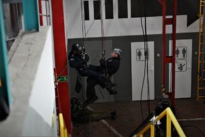zdjęcie przedstawia dwóch policjantów w mundurach zwisających z konstrukcji na linach