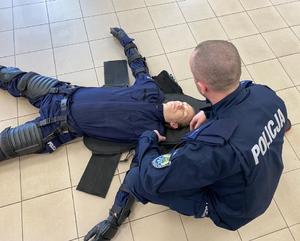 Na zdjęciu policjant w trakcie omawiania zasad udzielania pomocy rannemu policjantowi