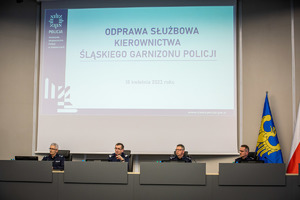 Na zdjęciu umundurowani policjanci w auli komendy wojewódzkiej, w tle prezentacja multimedialna i napis odprawa służbowa kierownictwa śląskiego garnizonu policji.