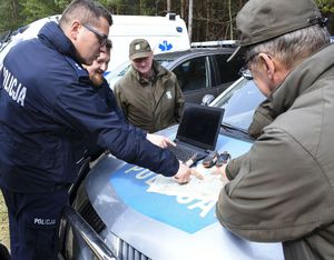 Policjanci zaznaczają z leśnikami obszar poszukiwań na mapie