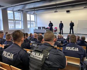 zdjęcie przedstawia salę szkoleniową, widoczni policjanci siedzący na widowni oraz stojący przed nimi.