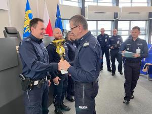 zdjęcie przedstawia Komendanta wręczającego policjantom nagrody.