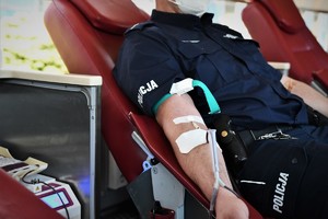 zdjęcie przedstawia policjanta w mundurze w trakcie oddawania krwi
