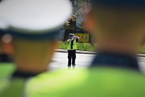 Zdjęcie. Umundurowany policjant kierujący ruchem na skrzyżowaniu