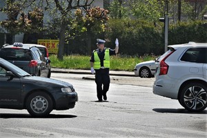 Zdjęcie. Umundurowany policjant kierujący ruchem na skrzyżowaniu