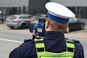 zdjęcie przedstawia policjanta dokonującego pomiaru prędkości