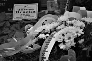 Wieńce i kwiaty na mogile obok tabliczki nagrobnej