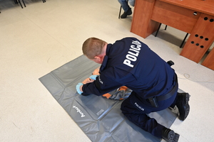 zdjęcie przedstawia policjanta w trakcie symulacji udzielania pierwszej pomocy