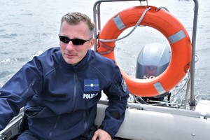Zdjęcie. Widoczni umundurowani policjanci w łodziach motorowych na akwenie