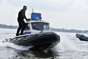 Zdjęcie. Widoczni umundurowani policjanci w łodziach motorowych na akwenie