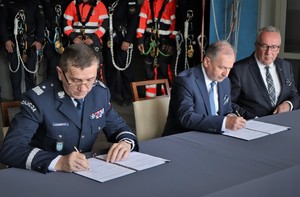 Na zdjęciu komendant wojewódzki oraz prezes siedzą przy stole i podpisują porozumienie.