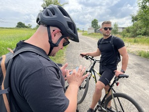 mężczyzna stojąc przy rowerze patrzy w ekran telefonu