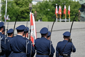 Zdjęcie przedstawia umundurowanych policjantów stojących w szeregu ze sztandarem.