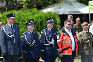 Zdjęcie. Widoczni umundurowani policjanci oraz inne służby mundurowe i uczestnicy uroczystości na Skwerze 100-lecia powstań śląskich w parku śląskim