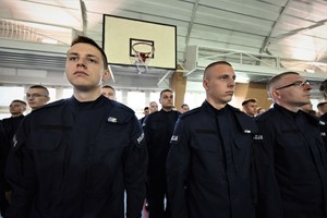 Zdjęcie. Widoczni stojący na sali sportowej umundurowani policjanci