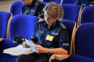 Zdjęcie. Umundurowany policjant podczas rozwiązywania testu na auli