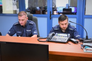 Dwaj umundurowani policjanci siedzą przy biurku.