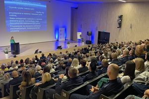 Uczestnicy konferencji siedzący na widowni przed sceną, na której odbywają się wykłady