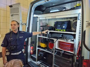 policjant prezentujący wyposażenie policyjnego ambulansu pogotowia ruchu drogowego