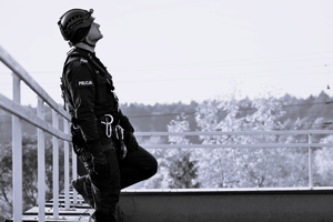 Zdjęcie. Policjant z mundurze i kasku stoi na dachu