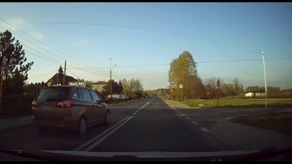 Zdjęcie z kamery samochodowej. Z lewej strony nagrywające widzimy samochód osobowy, który wyprzedza nagrywającego na skrzyżowaniu.