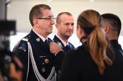 Zdjęcie. Mężczyzna przypina medal do munduru komendanta policji.