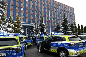 Zdjęcie. Oznakowane radiowozy zaparkowane przed budynkiem Komendy Wojewódzkiej Policji w Katowicach, obok których stoją umundurowani policjanci.