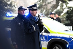 Komendant Wojewódzki Policji w Katowicach przed mikrofonem przed budynkiem komendy, na drugim planie policjant w mundurze