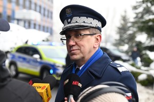 Zdjęcie. Komendant Wojewódzki Policji w Katowicach przed mikrofonem reporterów przed budynkiem komendy