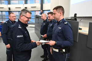 zdjęcie przedstawia policjanta, który odbiera gratulacje od Komendanta