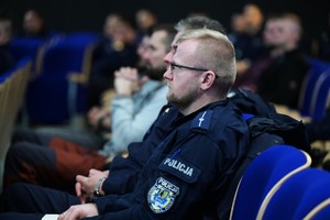 Umundurowany policjant siedzi na auli na wykładzie.
