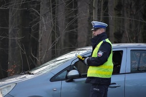 na zdjęciu policjant ruchu drogowego bada trzeźwość kierującego