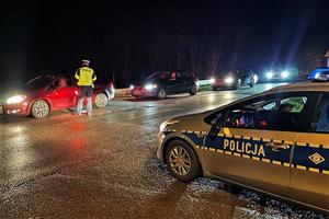 na zdjęciu policjant sprawdza trzeźwość widać radiowóz i kilka pojazdów czekających na badanie