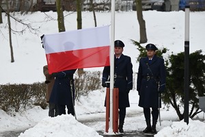 Policjanci rozkładają flagę Polski.