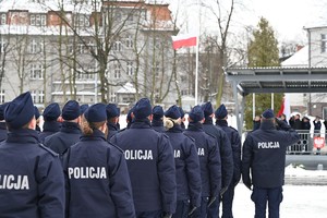 Policjanci spoglądają na biało-czerwoną flagę.