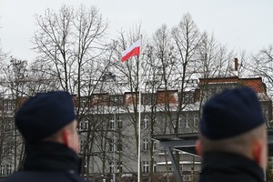Biało-czerwona flaga, którą obserwują policjanci.