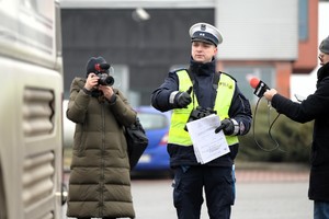Zdjęcie przedstawia umundurowanego policjanta z dokumentami w ręku. Obok stoi kobieta.