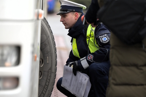 Zdjęcie przedstawia umundurowanego policjanta przeprowadzającego kontrolę autokaru.