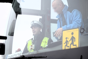Zdjęcie przedstawia umundurowanego policjanta siedzącego w autokarze. Obok niego siedzi mężczyzna.