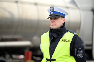 Zdjęcie przedstawia umundurowanego policjanta w kamizelce odblaskowej.