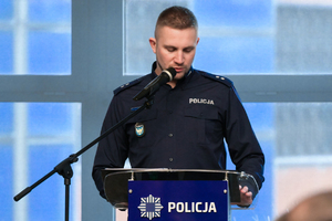 policjant przemawiający do mikrofonu podczas narady rocznej