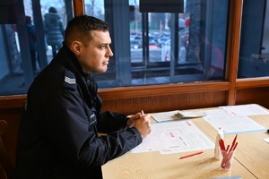 Policjant w mundurze siedzi przy stoliku.