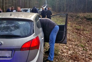 Pseudokibice zatrzymani przez policjantów przy samochodach w lesie