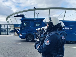 Umundurowani policjanci na tle policyjnego pojazdu i Stadionu Śląskiego